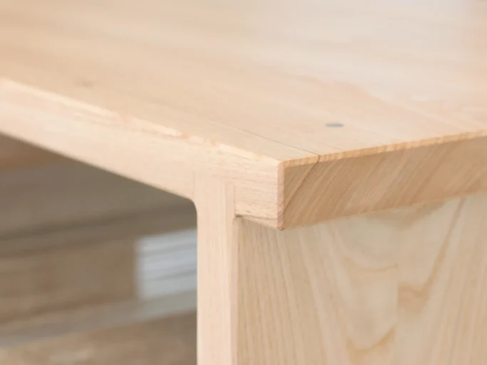 Recoin en bois clair d'une table, mettant en avant un design minimaliste et épuré.