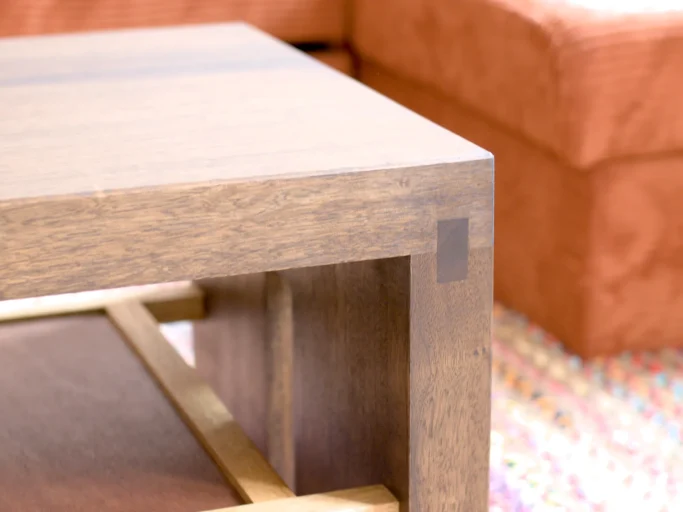 Table en bois avec coin en gros plan, arrière-plan d'un canapé orange.