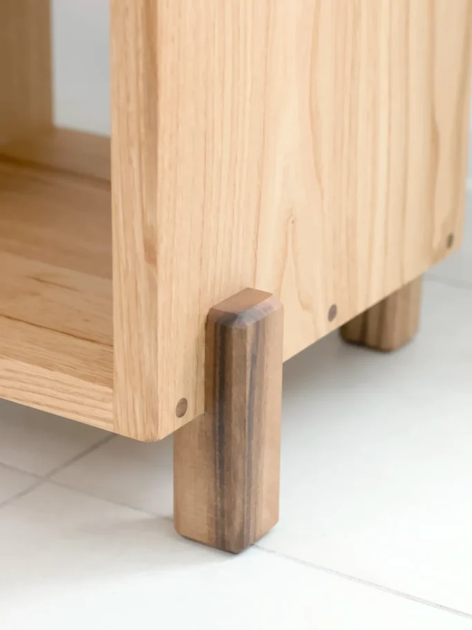 Support en bois clair avec pieds en bois foncé, sur un sol carrelé clair.