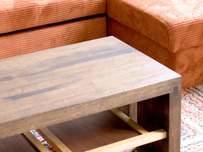 Table en bois foncé près d'un canapé orange, sur un tapis coloré.