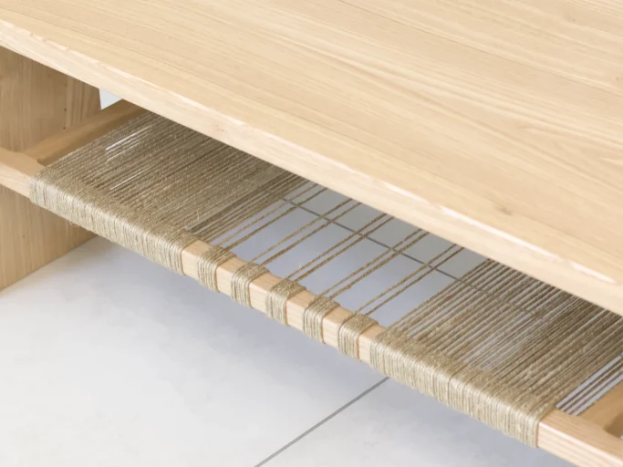 Table en bois clair avec un espace de rangement en bas, tressé avec des cordes.