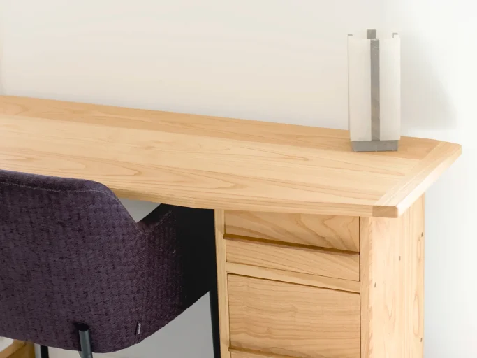 Bureau en bois clair avec une chaise violette et une lampe moderne sur le coin.