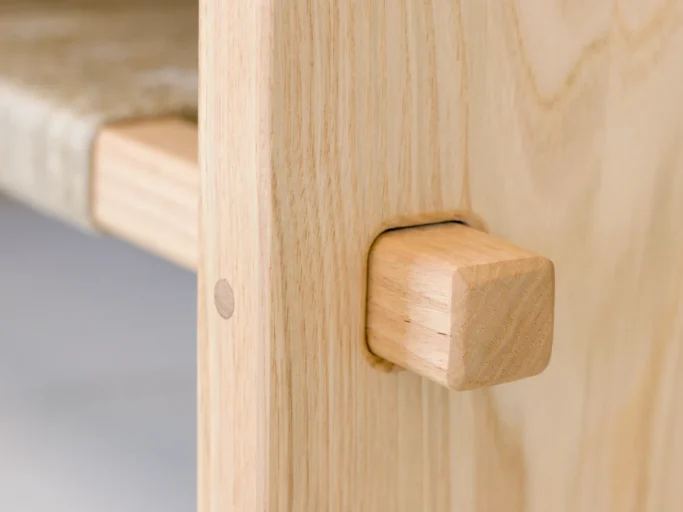 Détail d'un coin d'un meuble en bois clair avec un joint en bois carré.